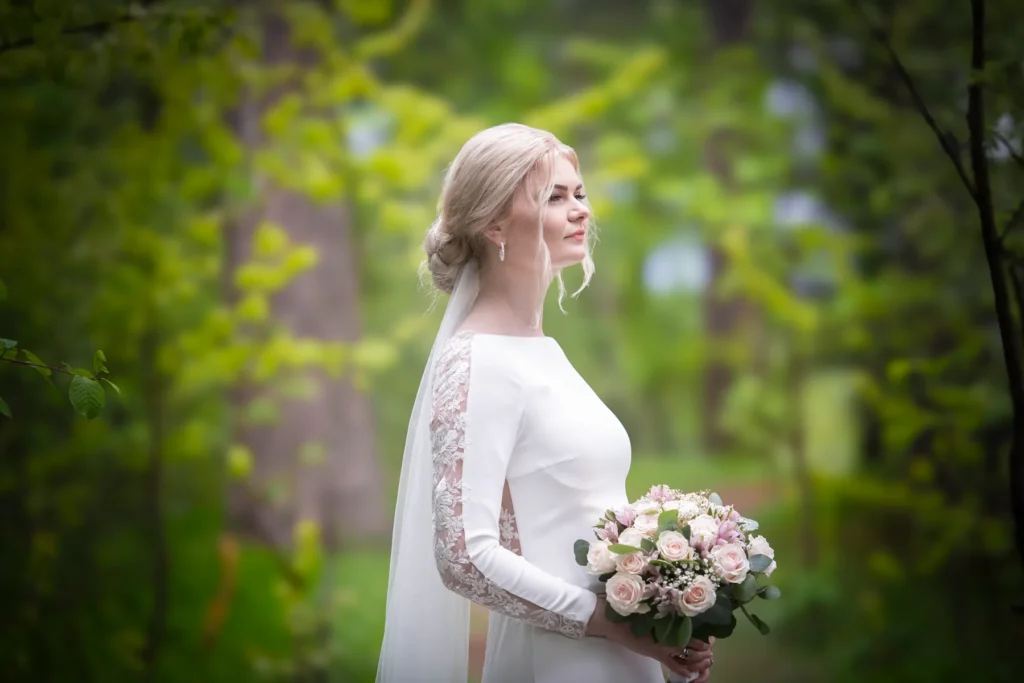 Bryllupsfotograf Oslo – brud med slør og rosa bukett i skogkledd landskap