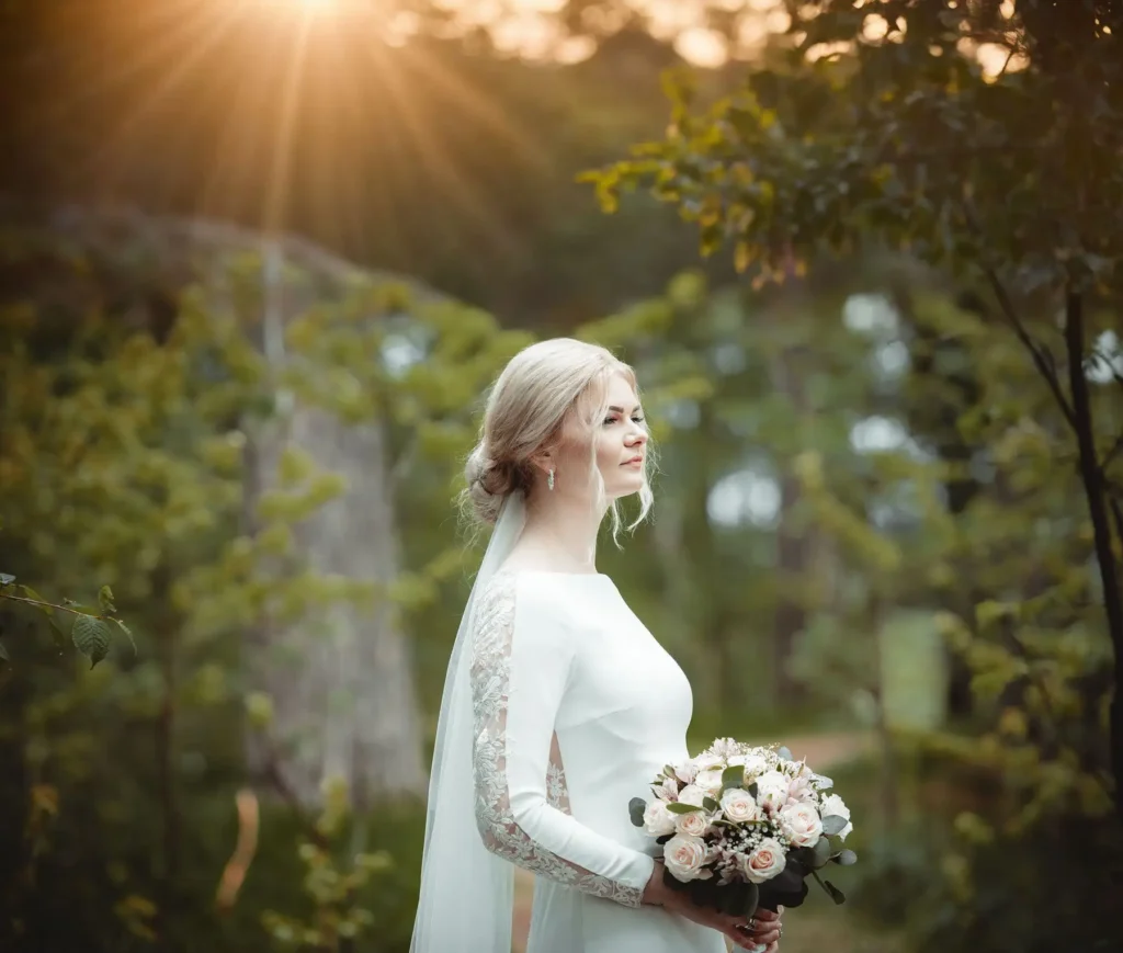 Bryllupsfotograf Oslo – brud med slør og rosa bukett i skogkledd landskap