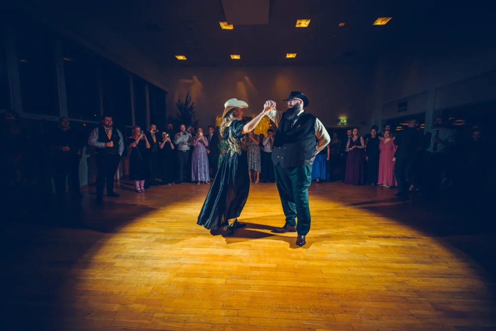 Bryllupsfotograf Oslo – øyeblikksbilde fra dansegulvet med par i western-inspirert antrekk omgitt av gjester i spotlight
