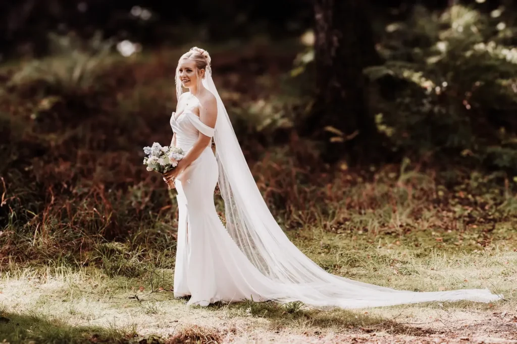 Brud med langt slør – bryllupsfotograf fanger varme og lys i naturlig omgivelser